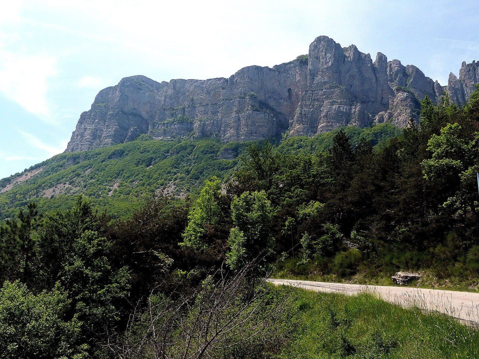 The cliffs and limestone pinnacles of the Trois Becs rise above the wooded slopes of the Saoû forest.