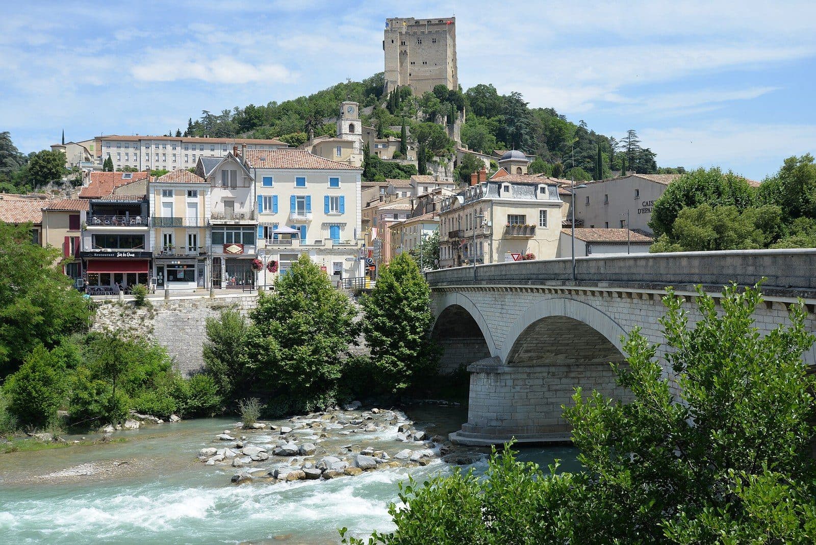 The Crest tower rises above the old town and its colourful façades, over the Drôme and its bridge.