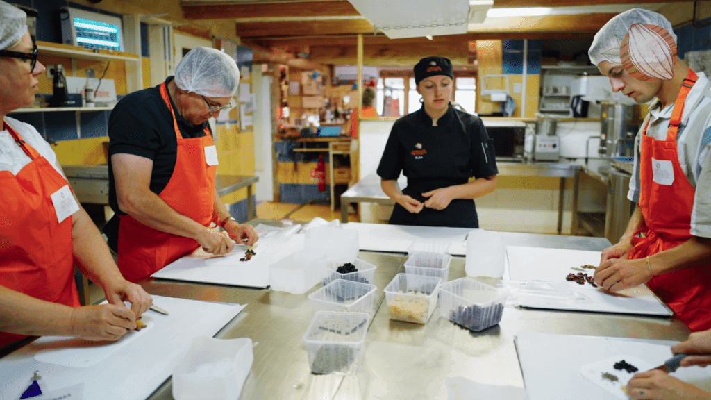 Des participants en tablier confectionnent leurs chocolats autour d’une chocolatière